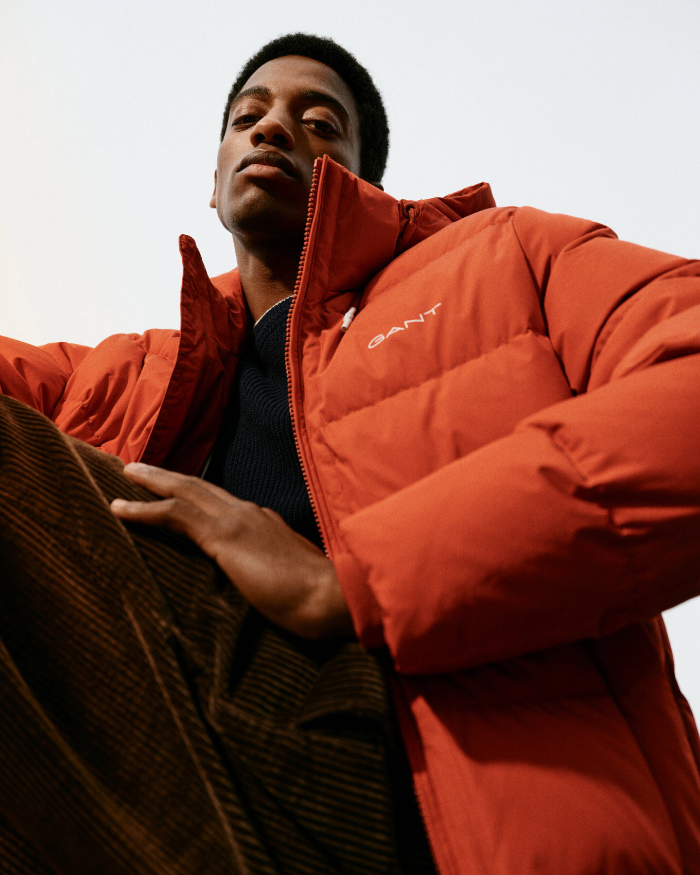 Man is wearing Alta Down Jacket on color red spice, Cotton Cashmere Crew Neck Sweater in black and Wide Volume Corduroy Pants in color rich brown. 